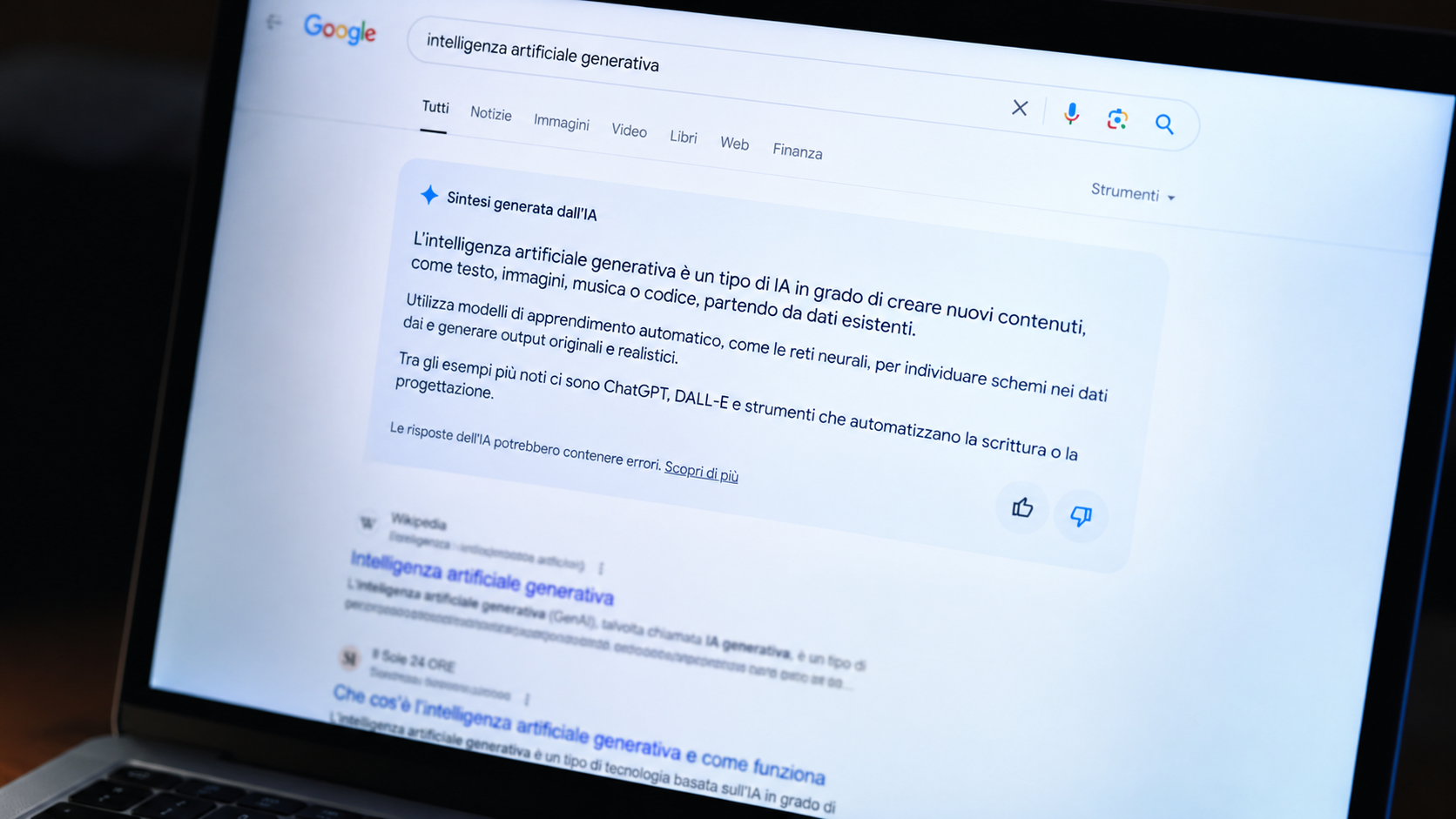 Primo piano di uno schermo di laptop che visualizza una pagina di risultati di ricerca con un riquadro di sintesi generata dall'intelligenza artificiale in evidenza sopra un elenco di collegamenti sfocati.