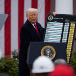 Donald Trump durante un discorso sui dazi reciproci degli Stati Uniti, con la tabella delle tariffe applicate ai principali partner commerciali sullo sfondo della bandiera americana