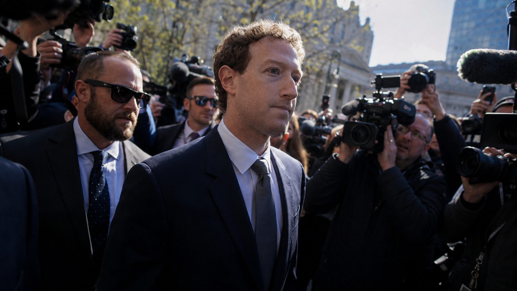 Mark Zuckerberg circondato da giornalisti, fotografi e operatori televisivi durante un’uscita pubblica, con telecamere e microfoni puntati verso di lui.