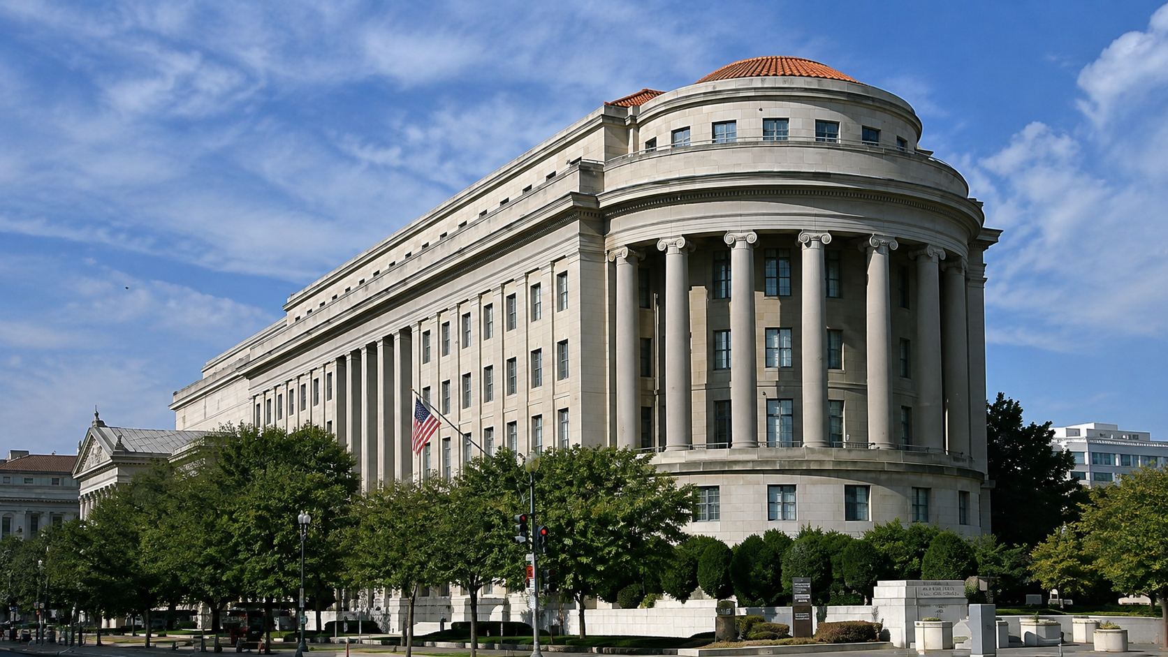 Facciata della Federal Trade Commission a Washington, edificio istituzionale neoclassico con colonne e bandiera americana sotto un cielo azzurro.