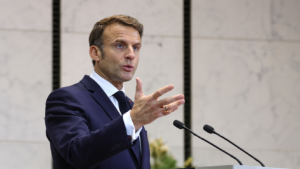 Emmanuel Macron durante un intervento pubblico, mentre parla al microfono e gesticola con una mano.