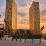 Facciata della Corte di giustizia dell’Unione europea a Lussemburgo, con le due torri dorate illuminate dalla luce del tramonto e le bandiere europee davanti all’edificio.