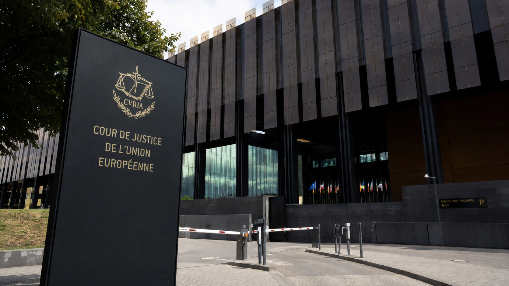 Facciata della Corte di giustizia dell’Unione europea a Lussemburgo, ripresa dal basso in luce diurna, con l’edificio istituzionale e le bandiere degli Stati membri sullo sfondo.